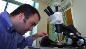 Pedro Irazoqui, an assistant professor of biomedical engineering at Purdue, uses a "radio frequency probe station" to test tiny circuits in a new miniature device designed to be implanted in the brain to predict epileptic seizures. The research focuses on a transmitter three times the width of a human hair to be implanted below the scalp to detect the signs of a seizure before it occurs. The system will record neural signals relayed by electrodes in various points in the brain. (Purdue News Service photo/David Umberger)