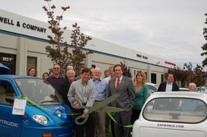 Taylor Smith cuts the green ribbon for a new ZAP electric car dealership that opened today in Silicon Valley. San Carlos Mayor Tom Davis to his left and the Chamber of Commerce welcomed the new business and tried out the new electric cars, trucks, scooters, and mopeds from Bay Area electric vehicle manufacturer ZAP.