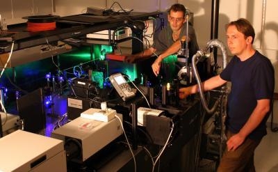 University of Utah physicists John Lupton and Christoph Boehme use green and blue laser beams to "excite" a small piece of an organic or "plastic" polymer (glowing orange near Boehme's right hand) that may serve as a light-emitting diode (LED) for computer and TV displays and perhaps lighting. A new study by Boehme, Lupton and colleagues sheds light on the maximum possible efficiency of organic LEDS. The physicists also found they could use the "spin" within electrons to control an electrical current -- a step toward developing "spin transistors" for a future generation of computers and electronics.

Photo Credit: Nick Borys