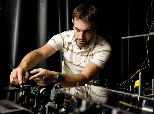 Physics graduate student David Press at the optical bench where his current experiments are running.