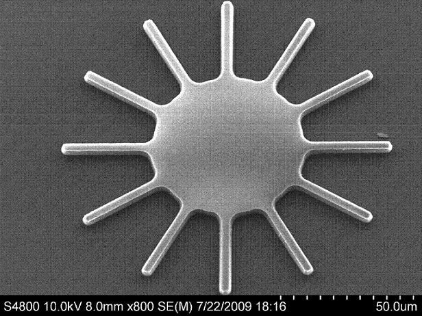 Researchers are developing a new class of tiny mechanical devices containing vibrating, hair-thin structures that could be used to filter electronic signals in cell phones and for other more exotic applications. The work is done inside a vacuum chamber sitting on top of a special vibration-absorbing platform critical to making the precise measurements. A tiny prototype, roughly comparable in size to a grain of sand, is pictured on the monitor at right. The device is an example of a microelectromechanical system, or a MEMS, which contains tiny moving parts. (Birck Nanotechnology Center, Purdue University)