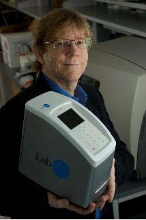 Rice Professor John McDevitt holds the LabNow device to read nano-bio-chips that will look for signs of oral cancer and other diseases. By Jeff Fitlow.