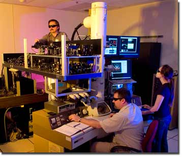 Making adjustments to the dynamic transmission electron microscope. From left: Curtis Brown, Thomas LaGrange and Judy Kim.