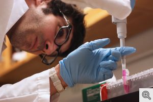 Remy Elbez, a doctoral student in applied physics, takes a sample of a solution that contains magnetized cervical cancer cells. He will place several drops of the solution in a special magnetic field. Then, after placing the whole apparatus under a microscope, he can watch the cells spin on a screen and determine their shape and status from their rotation rates. This new technique could help doctors understand the process of cancer metastasis. Photo by Nicole Casal Moore