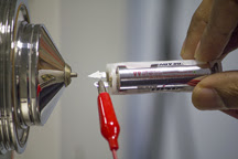 A carbon nanotube-coated paper triangle placed on an ionization source charged by a small battery is held in front of a mass spectrometer. Researchers at Purdue University and the Indian Institute of Technology Madras studied the use of carbon nanotubes to advance ambient ionization techniques.Purdue University photo/Courtesy of Thalappil Pradeep