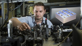 Dr. Kruk is next to a diagram of the metamaterial structure.

Image Stuart Hay, ANU