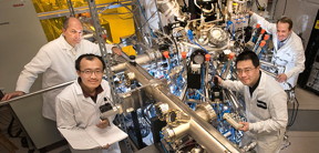 (Clockwise from left) Brookhaven Lab physicists Ivan Bozovic, Anthony Bollinger, and Jie Wu, and postdoctoral researcher Xi He with the atomic layer-by-layer molecular beam epitaxy system used to synthesize more than 2,500 thin films of a copper-oxide compound called LSCO. The team studied LSCO to understand why it can become superconducting at a much higher temperature than the ultra-chilled temperatures required by conventional superconductors.